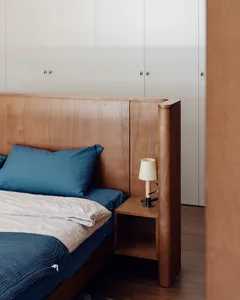 Minimalist bedroom with a wooden headboard and blue bedding.