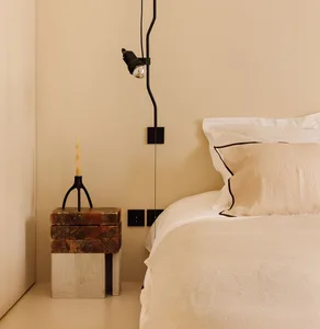 A modern bedroom with neutral tones, minimalist design, and a cozy atmosphere. Includes a bed with white bedding, a stone nig
