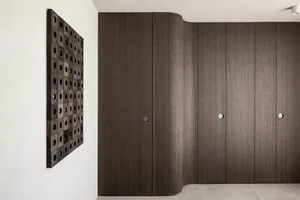Modern wooden cabinets with patterned wall art on a white wall