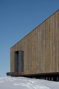 A modern industrial building exterior with wood siding and a raised platform.