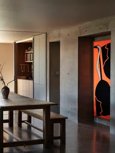 A modern minimalist interior with concrete walls and a wooden dining table.