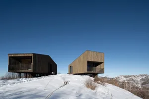 Two modern residences with wooden cladding situated on a snowy hillside