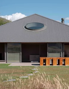 Modern residential home with metallic roof and large glass windows.