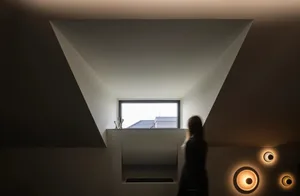 A modern interior design featuring a concrete wall with a large window and unique lighting fixtures.