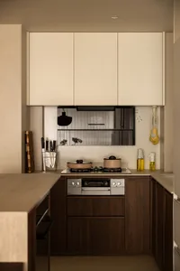 Modern minimalist kitchen with wood and metal accents featuring a countertop, cabinets, and an oven.