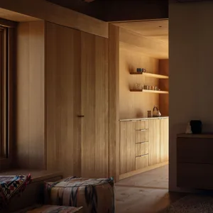 A modern, minimalist kitchen with wooden cabinets and shelves