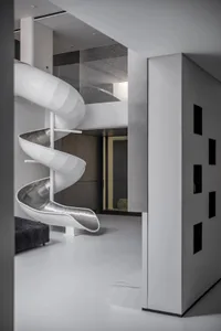 White and metallic spiral slide in minimalist living room.