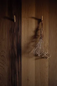 Dried flowers hanging from wooden hooks on warm wooden wall