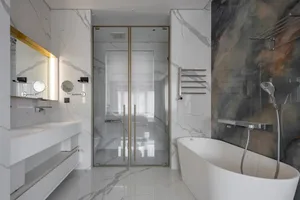Modern bathroom with marble walls and floor, featuring a freestanding bathtub, a glass-enclosed shower, and a floating vanity