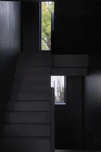 A modern black staircase with wooden steps in a dark interior space.