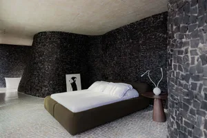 Modern bedroom with minimalist design featuring a concrete wall and floor.