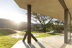 Sunlit modern exterior of a luxury retreat with concrete and glass materials.