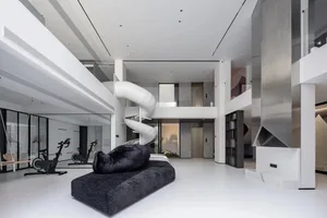 Modern living area with industrial design features, including concrete walls and a spiral staircase.
