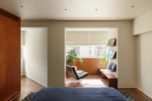 A modern minimalist bedroom with wooden walls and a grey bed.