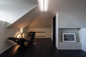 Modern minimalist living room featuring a wooden floor and black lounge chair.