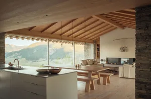 A modern residential space featuring wood, stone, and a large window with a view of the mountains.