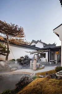 A traditional Chinese pavilion overlooking a serene river with stone elements and a misty landscape.