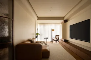 Modern minimalist living room featuring a brown leather sofa, a black flat-screen TV, and a wooden coffee table, with white v