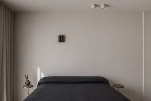 Modern minimalist bedroom with grey fabric bedspread and side tables.