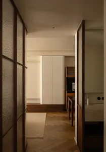 Modern minimalist bedroom featuring light-colored wooden floors, brass accents, and white cabinets.