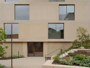 Modern minimalist building entrance with concrete walls and large glass windows.