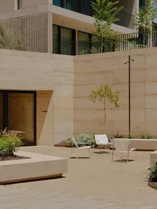 Outdoor patio area with concrete walls, metal chairs, and a tree in the center.
