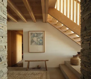 A modern staircase with wooden stairs, a wooden bench, and a geometric art piece.