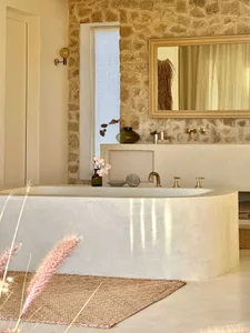Modern minimalist bathroom featuring a concrete bathtub and stone wall