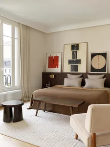 Minimalist bedroom with a brown bed, artwork, and mixed materials in a modern design.