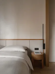 A minimalist bedroom featuring simple furniture and wooden elements.