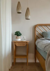 A minimalist bedroom featuring a wooden console table with cane-weave drawers and a potted plant on top.