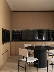 Modern kitchen with minimalist design featuring wooden cabinets and glass elements.