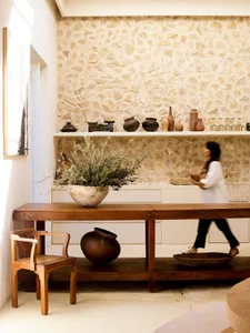 A minimalist residential kitchen featuring a wooden counter and stone wall with various decorative items.