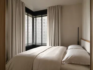 A modern bedroom featuring a comfortable sofa upholstered in a neutral-toned fabric.