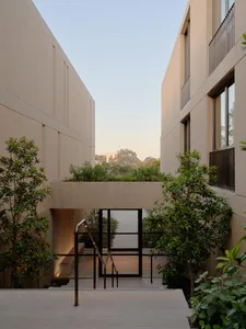 Concrete entrance with stairs, plants, and glass doors.