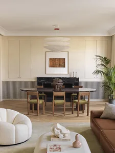A modern living and dining room featuring wooden furniture, marble accents, leather seating, fabric textiles, metallic elemen