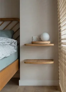 A minimalist bedroom featuring floating shelves made of wood, with a white spherical lamp, electrical outlets, and a bed with