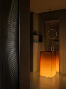 Modern bathroom with glass fixtures and illuminated orange lights.