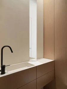 Modern bathroom with a black faucet and a long, rectangular wooden cabinet.