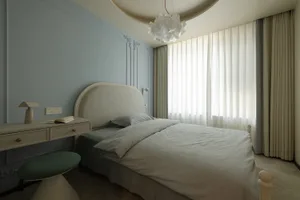 A modern bedroom with a fabric bed and curtains.