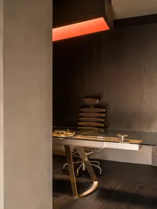 Modern home office featuring glass and metal desk and chair, illuminated by red light.