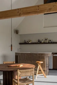 Modern kitchen bar featuring a wooden cornice and a round wooden table with a chopping board.