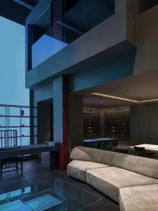 Modern living room featuring leather couches, glass table, and concrete columns.