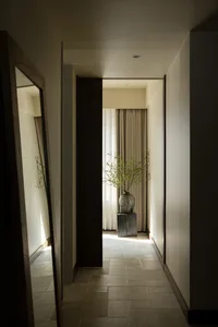 Modern minimalist entryway with white walls, stone flooring, and wooden accents.