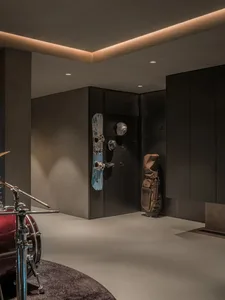 A modern music room featuring a drum set and a wall-mounted sports gear rack with snowboards and helmets.