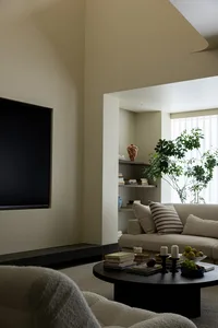 A modern living room with a neutral color palette featuring a couch, coffee table, and bookshelf.