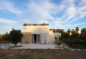 A modern residential exterior featuring white stucco and stone elements.