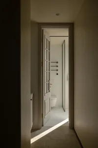 A minimalist bathroom with white tiles and a toilet.