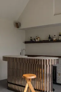 A modern bar with metallic textured surfaces and a wooden stool.