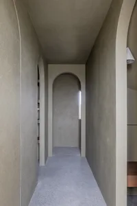 Modern interior space featuring a minimalist design with concrete walls and a long hallway with arches and a skylight.